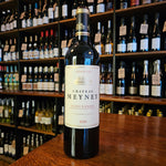 A wine bottle standing on a wooden table with facing label.