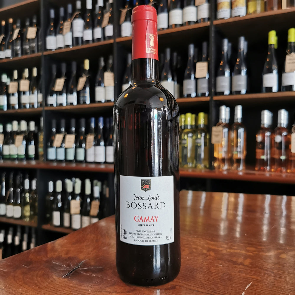 A wine bottle standing on a wooden table with facing label.