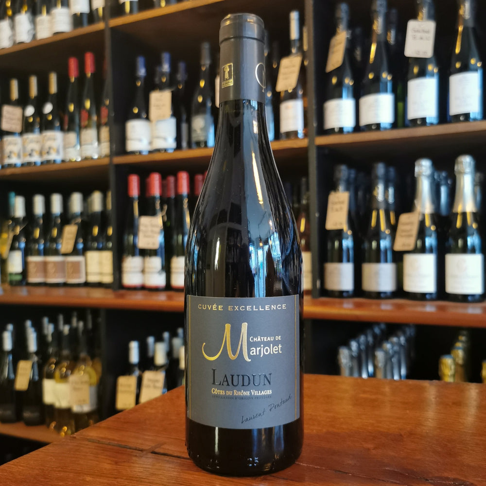 Wine Bottle standing on a wooden table in the front of wine shelves in a wine shop.