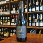 Wine Bottle standing on a wooden table in the front of wine shelves in a wine shop.